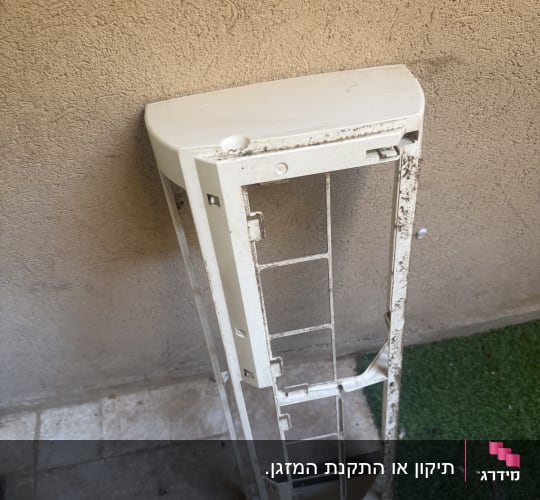 חלק ממזגן מונח על הרצפה ליד קיר